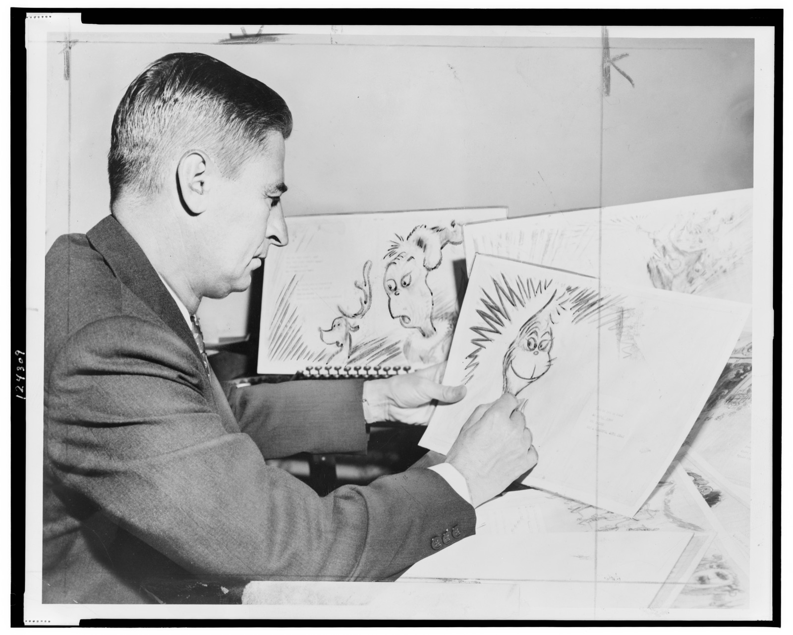 Dr. Seuss (Ted Geisel) at work on a drawing of a grinch, the hero of his forthcoming book, "How the Grinch Stole Christmas"