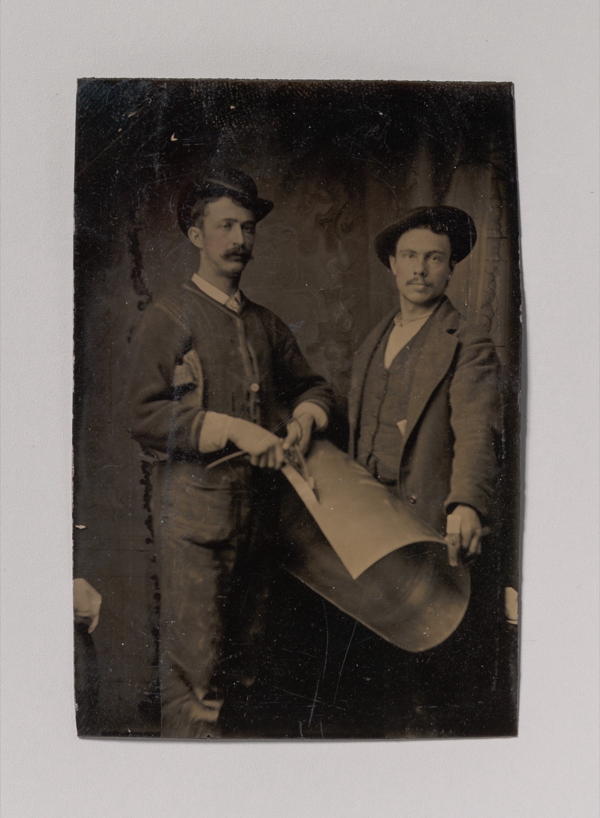 [Two Tinsmiths Cutting a Curled Sheet of Metal] — Unknown
