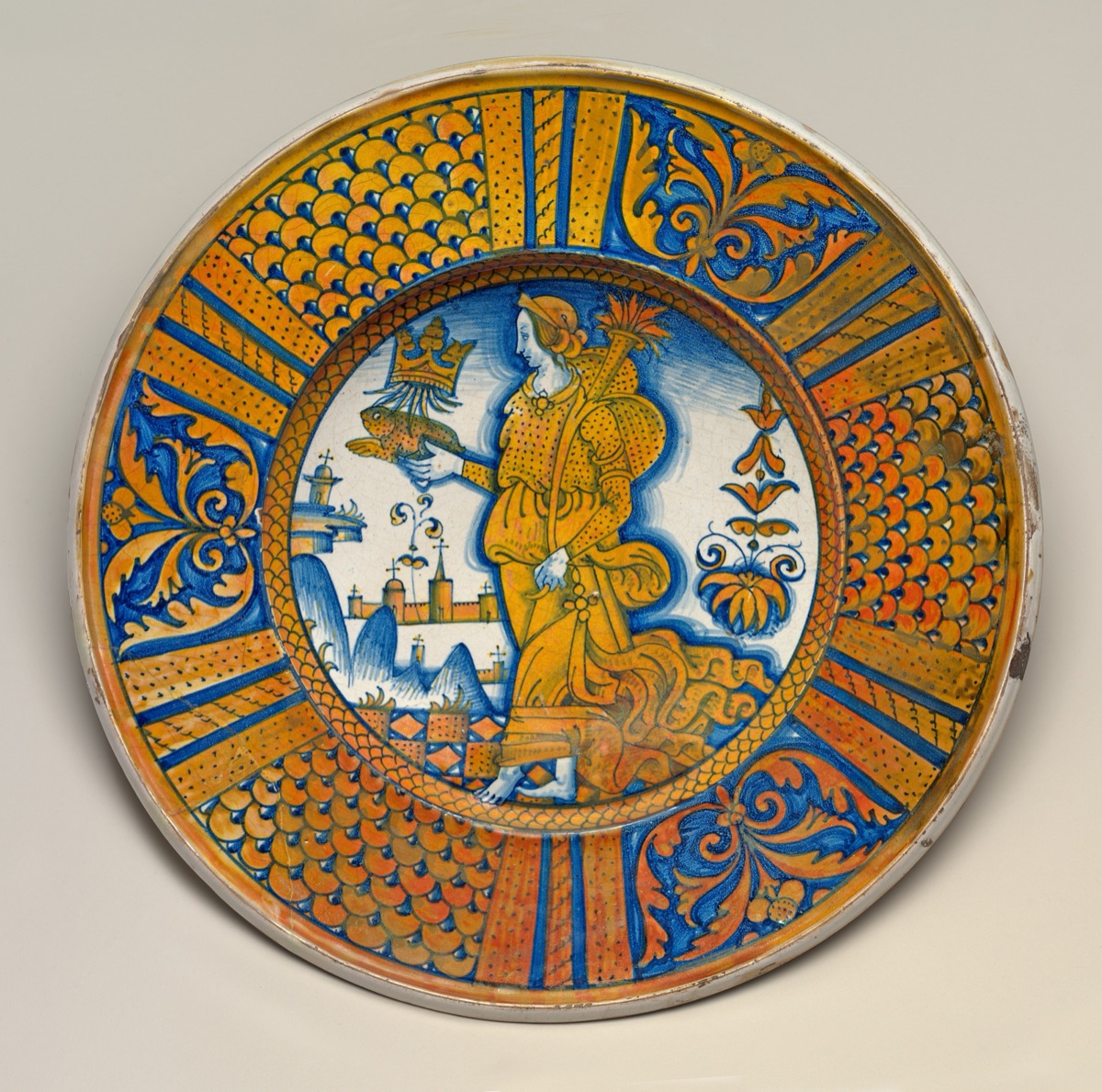 Large dish with segmental border of plant sprays and scale pattern; in the center, an emblematic female figure holding a crowned toad and cornucopia — Deruta 16th Century