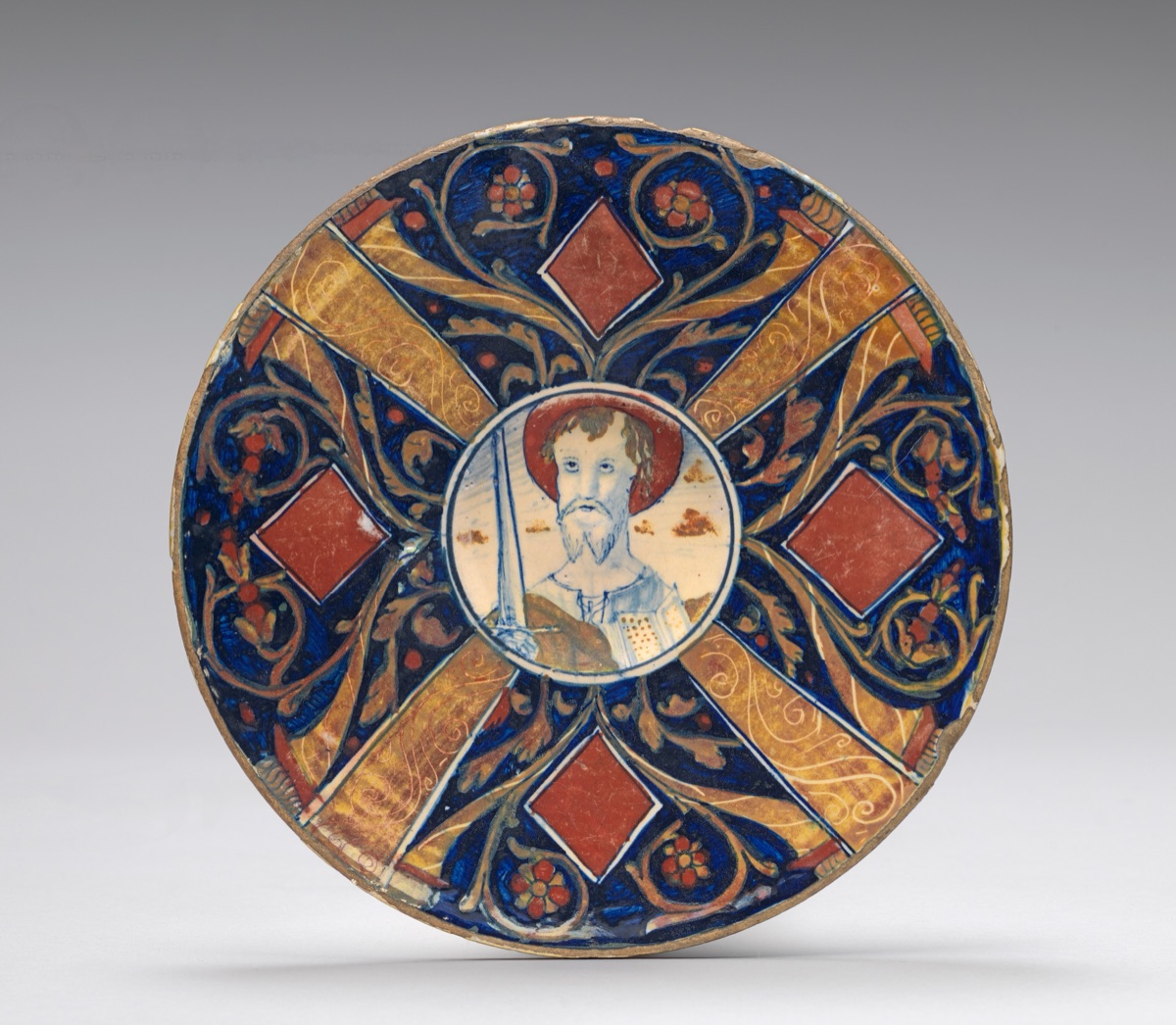 Small flat plate with border of cornucopias, scrollwork, and lozenges in four sections; in the center, a bust of Saint Paul with raised sword — related artist: Maestro Giorgio Andreoli of Gubbio; Italian 16th Century; Attributed to Workshop of Maestro Giorgio Andreoli of Gubbio